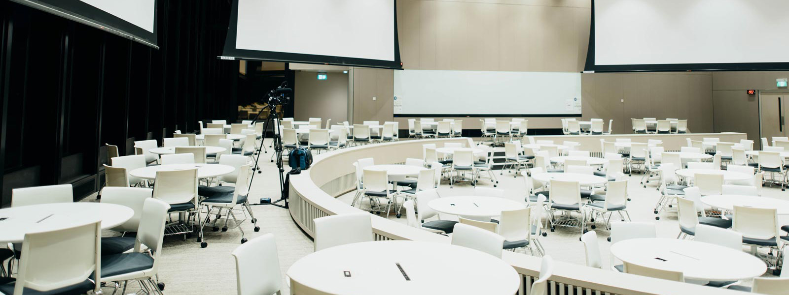 Veranstaltungsraum mit vielen Tischen und Leinwänden